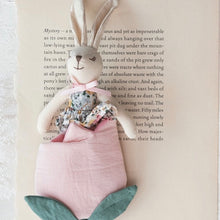 Load image into Gallery viewer, A white bunny plushie wearing a blue floral dress , in a pink tulip bag on an opened book page.