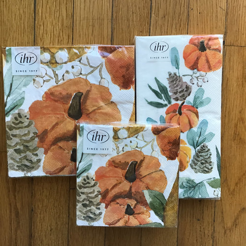 Three different sized paper napkin sets wrapped in plastic packaging with a white label in the upper left corner . 
