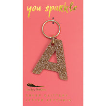 Load image into Gallery viewer, Gold glittery letter &quot;A&quot; keychain on a pink card with &quot;you sparkle&quot; in gold text, displayed on a white background. 