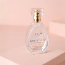 Load image into Gallery viewer, Snowdrop eau de parfum in a clear glass bottle with a gold collar and a transparent cap, shown on a powder pink background. 