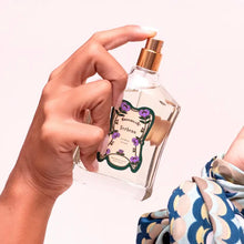 Load image into Gallery viewer, Hand holding Granado Verbena cologne bottle with gold spray top and decorative purple floral label against a white background. 