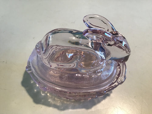 A pink glass dish in the shape of a bunny on a cream background.