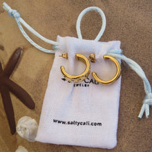 Load image into Gallery viewer, Gold hoop earring set on top of white jewelry bag with &quot;www.saltycali.com&quot; text on a beach background.