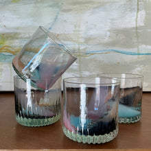Load image into Gallery viewer, Speak EZ Cups hand-blown glass set of four with heavy textured bases and assorted peach, steel blue, pink, and mint accents, one stacked inside another on wooden surface against an abstract background. 