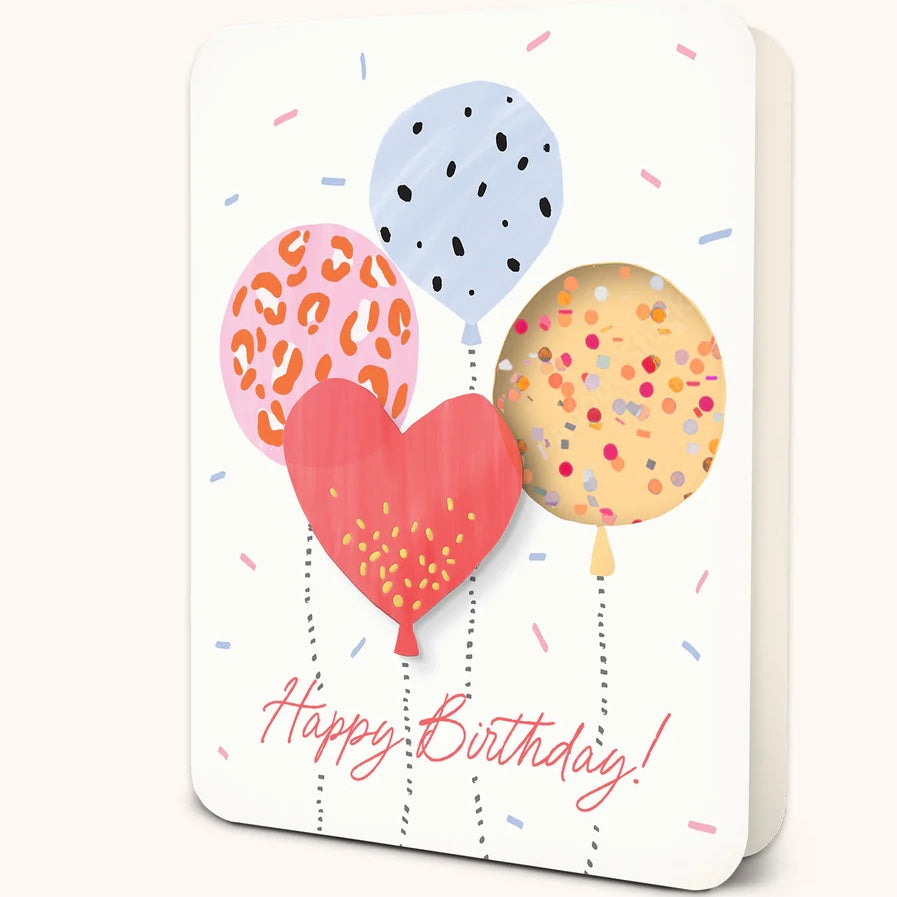 A slightly opened white greeting card with four colorful balloons, pink and blue confetti, and 