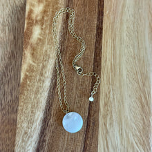Load image into Gallery viewer, Gold chained necklace with a round mother of pearl pendant on a wooden surface.