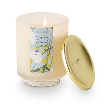 Load image into Gallery viewer, Fresh Sea Salt Candle, frosted glass jar with lit white wax candle on clear pedestal base and pale blue floral label, round gold-tone brass lid beside candle, displayed against white background. 