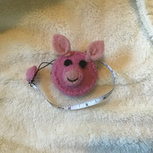 Load image into Gallery viewer, Pink pig felt measuring tape on a beige carpet.