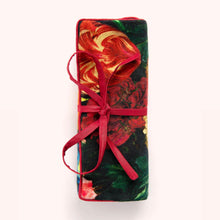 Load image into Gallery viewer, Velvet jewelry roll in a rich red and green floral pattern tied with a red ribbon, displayed against a white background.  