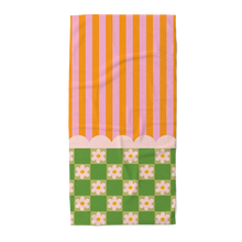 Load image into Gallery viewer, Beach towel with an orange and pink striped top and a green and white floral checkered patterned bottom, separated by a white scalloped design. On a black and gray checkered background.