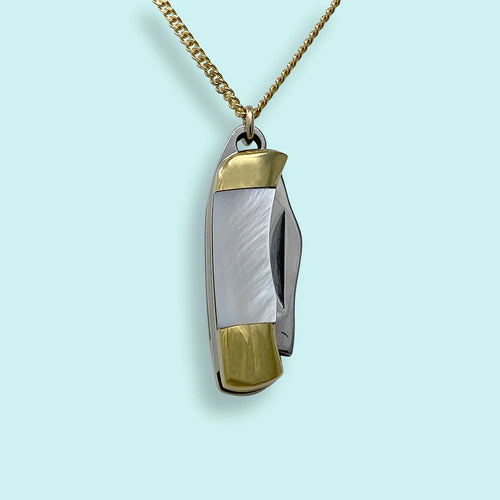 Silver and gold charm in the shape of a pocket knife on a gold chain. Light blue background. 