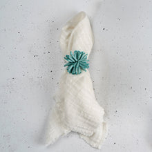 Load image into Gallery viewer, White cloth napkin secured with a sea-blue beaded floral napkin ring featuring a floral motif.