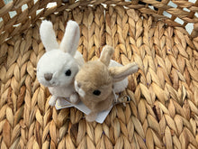 Load image into Gallery viewer, Hera and Zeus mini plush bunny bag charm with one white and one light tan bunny, black eyes, silver clip, displayed on a woven background. 