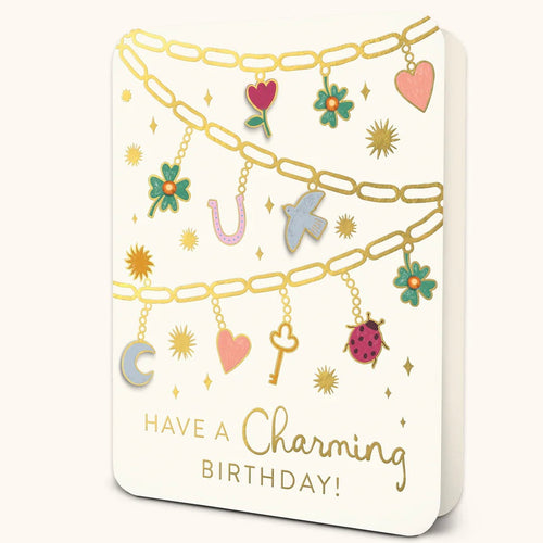 White greeting card featuring gold chain designs with colorful charms including hearts, flowers, a key, moon, horseshoe, bird, and ladybug. Text at the bottom reads 