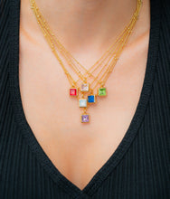 Load image into Gallery viewer, Model wearing layered 14K gold-dipped birthstone necklaces, each with a square glass crystal pendant in assorted colors, displayed against a black V-neck top.