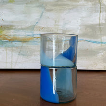 Load image into Gallery viewer, Splash Cup clear hand-blown glass set with abstract blue and light blue swirled design, stacked on one another on wooden surface against abstract background.  