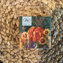 Load image into Gallery viewer, Set of harvest-themed cocktail napkins , wrapped in plastic packaging with a white label in the upper left corner. &quot;ihr&quot; and &quot;SINCE 1977&quot; in black on the  white label. Napkins on a woven brown surface.
Harvest theme includes an orange pumpkin, a green and purple cabbage, red berries, yellow sunflowers, and an orange butterfly ,with a black and tan background.