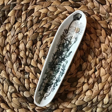 Load image into Gallery viewer, White ceramic cookie dish with a floral design on a woven surface.