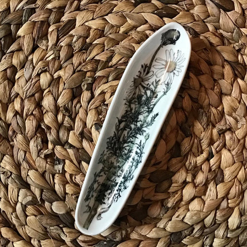 White ceramic cookie dish with a floral design on a woven surface.