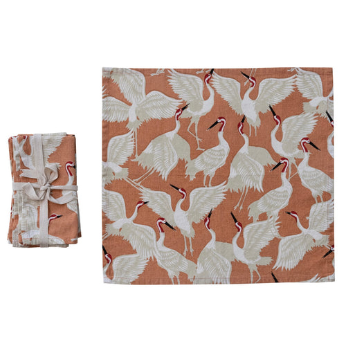 Stack of fabric napkins with a crane bird pattern folded and tied with ribbon, one  unfolded displayed on white background.