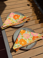 Load image into Gallery viewer, Two pink and orange floral napkins that&#39;s folded neatly on dinner plates . 