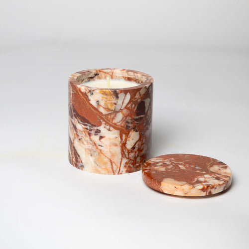 A  reddish brown marble candle holder with a white candle inside and a matching lid beside it, on a white background.