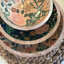 Load image into Gallery viewer, Enamel bowls stacked with largest bowl on bottom and smallest on top. Bottom and top bowl has a floral pattern in beige, green, and pink. Bowl in the middle has a floral pattern in dark green, light green, pink, and yellow. On a woven mat.