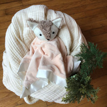 Load image into Gallery viewer, Peach colored plushie with a fox head cradled on a white muslin blanket, wooden background with greenery.