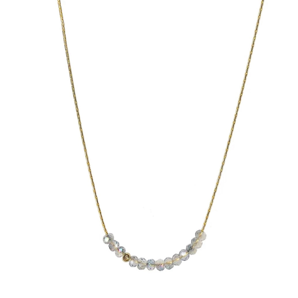 Necklace with small iridescent beads on a thin gold chain against a white background