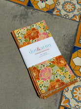 Load image into Gallery viewer, Dot and Army  pink and orange floral cloth napkin folded neatly on concrete and tile floor.
