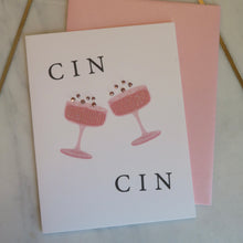 Load image into Gallery viewer, Greeting card with pink champagne glasses and sparkly bubbles and  &quot;CIN , CIN&quot;  text with a pink envelope  on a marble surface.