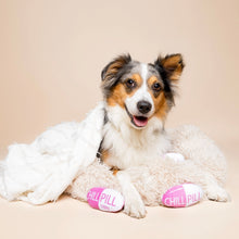 Load image into Gallery viewer, Dog lying on a plush dog bed covered with a soft white blanket, with two pink-and-white capsule-shaped "Chill Pill" plush dog toys in front, shown against a neutral background. 