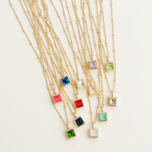 Load image into Gallery viewer, Collection of 14K gold-dipped birthstone necklaces arranged in a fan layout on a white surface, each featuring a square glass crystal pendant in assorted colors representing all twelve months.