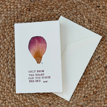 Load image into Gallery viewer, Colby Cards, lifestyle image of a white Lokta paper greeting card featuring a real pressed pink and golden-orange flower petal above the Rumi quote “Only From the Heart Can You Touch the Sky”  in dark burgundy lettering, displayed with a white envelope on a brown woven mat.
