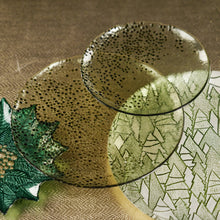 Load image into Gallery viewer, A small green glass plate overlapping a larger green glass plate, both featuring a raised dark green dotted texture. The larger plate overlaps a green poinsettia plate and a plate with a green Christmas tree design, all displayed on a gold textured surface. 