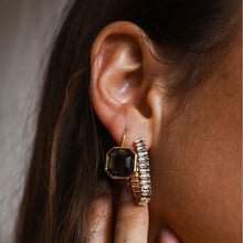 Load image into Gallery viewer, Gold-plated brass drop earring featuring a faceted octagon-cut green tourmaline stone in a thin bezel frame, shown worn on model's ear beside a second embellished hoop earring. 