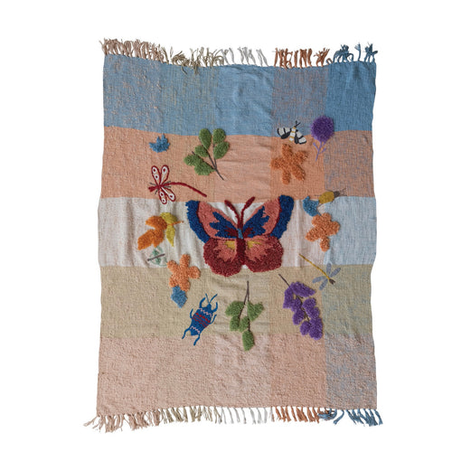A woven, tufted butterfly blanket with a multicolored pattern featuring a prominent butterfly design in the center, surrounded by floral and insect motifs, on a white background.