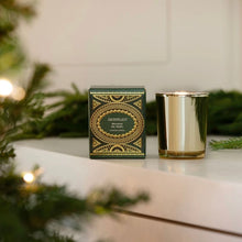 Load image into Gallery viewer, Metallic gold 2 oz. candle and its decorative hunter green and metallic gold box on a white surface with a blurred lit Christmas tree in the foreground.
