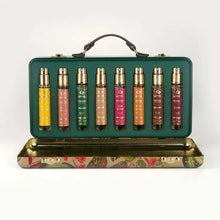 Load image into Gallery viewer, Granado Best-Sellers suitcase opened to display eight travel-size perfume sprays in assorted colors with gold spray tops inside a green case with brown handle on a white background. 