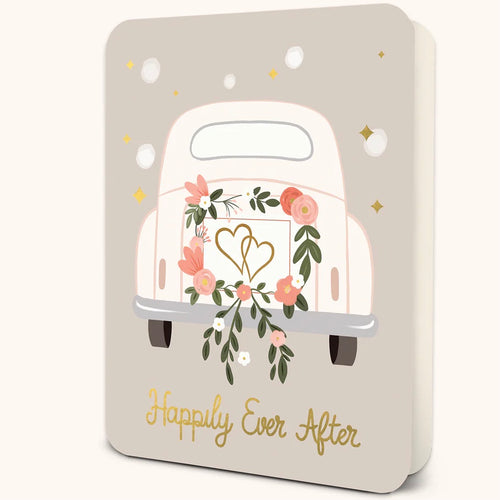 Slightly opened standing pale gray greeting card with white polka dots and gold stars.  In the middle of the card is the back end of white car. Car has a pink and green floral wreath with intertwined hearts on it.. 