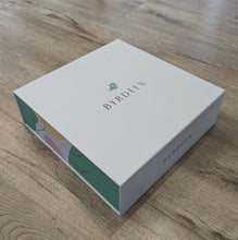 Load image into Gallery viewer, Closed Byrdeen gift box with a white lid and pastel abstract-patterned sides, displayed on a light wooden surface.  