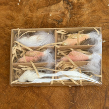 Load image into Gallery viewer, Set of six glass clip-on bird decorations in storage box with dividers and brown packaging strings. Birds have a white and pink body with gold glitter, and a white feather tail. On a brown wooden surface. 