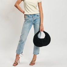 Load image into Gallery viewer, Model wearing a white short-sleeve top and light-wash jeans, holding a black suede crescent-shaped hobo bag at their side against a white background. 