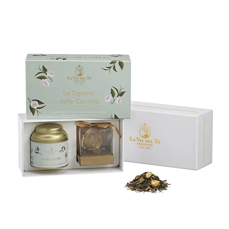 Tea gift set with a tea canister, an infuser, and loose tea leaves on a white background. Tea set is in a white box with a light green with white flowers and 