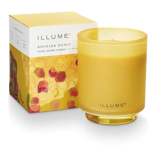 Yellow candle with 'ILLUME' branding next to its packaging on a white background