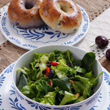 Load image into Gallery viewer, White melamine dinner bowl with a blue floral pattern containing salad, shown in a table setting with matching plates and two bagels.   