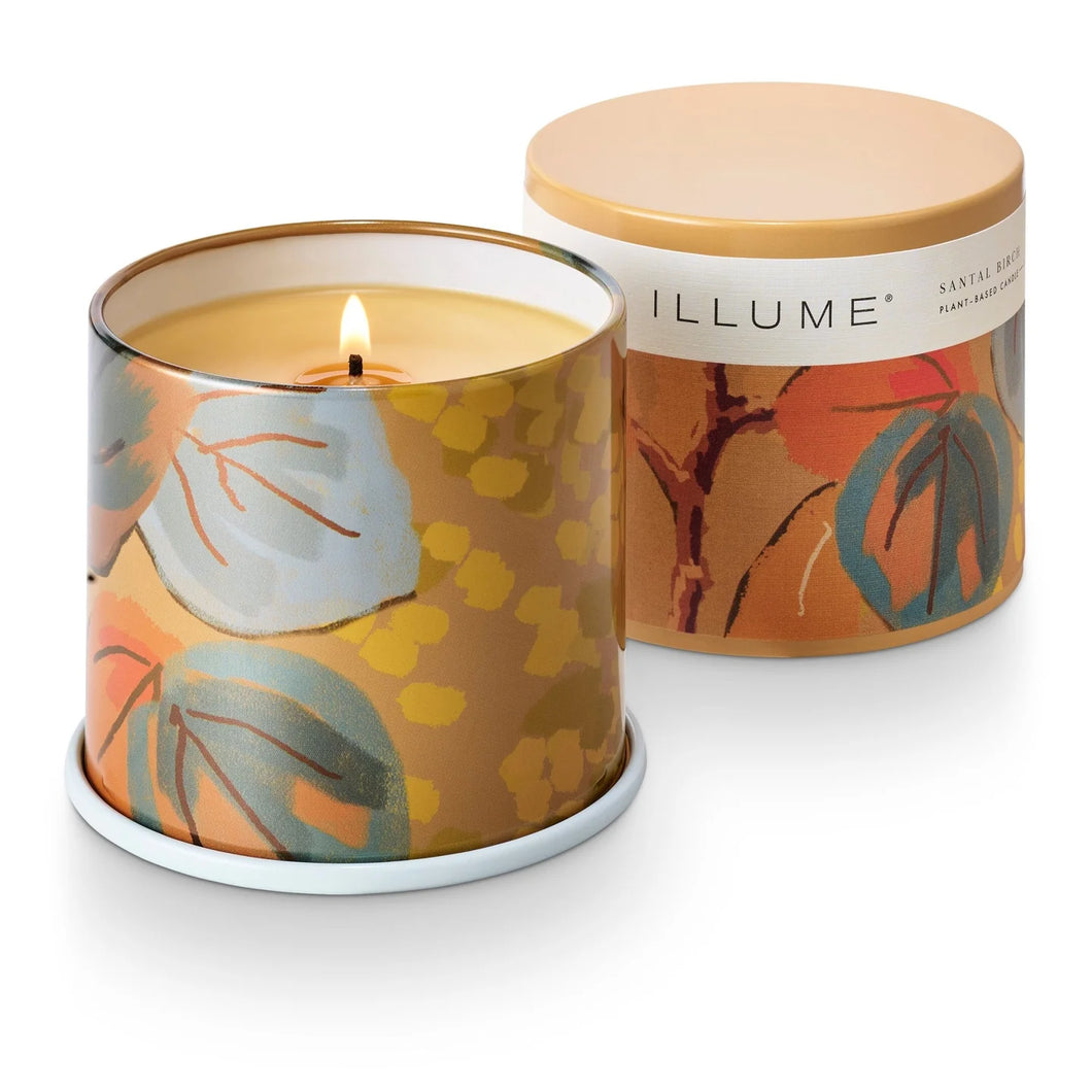 Illuminated candle with floral design in a decorative container on a white background
