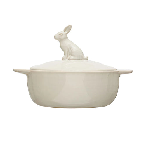A white stoneware baker with handles and a lid featuring a rabbit figure, on a white background.