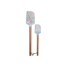 Load image into Gallery viewer, A big and a small baby blue silicone spatula joined together at the base of their wooden handles by a brown tie. Silicone end has a pink and blue floral pattern. White background. 