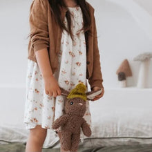 Load image into Gallery viewer, Child wearing a brown cardigan over a floral dress, holding a bunny rabbit with a mustard yellow knitted hat with white bedding in the background.